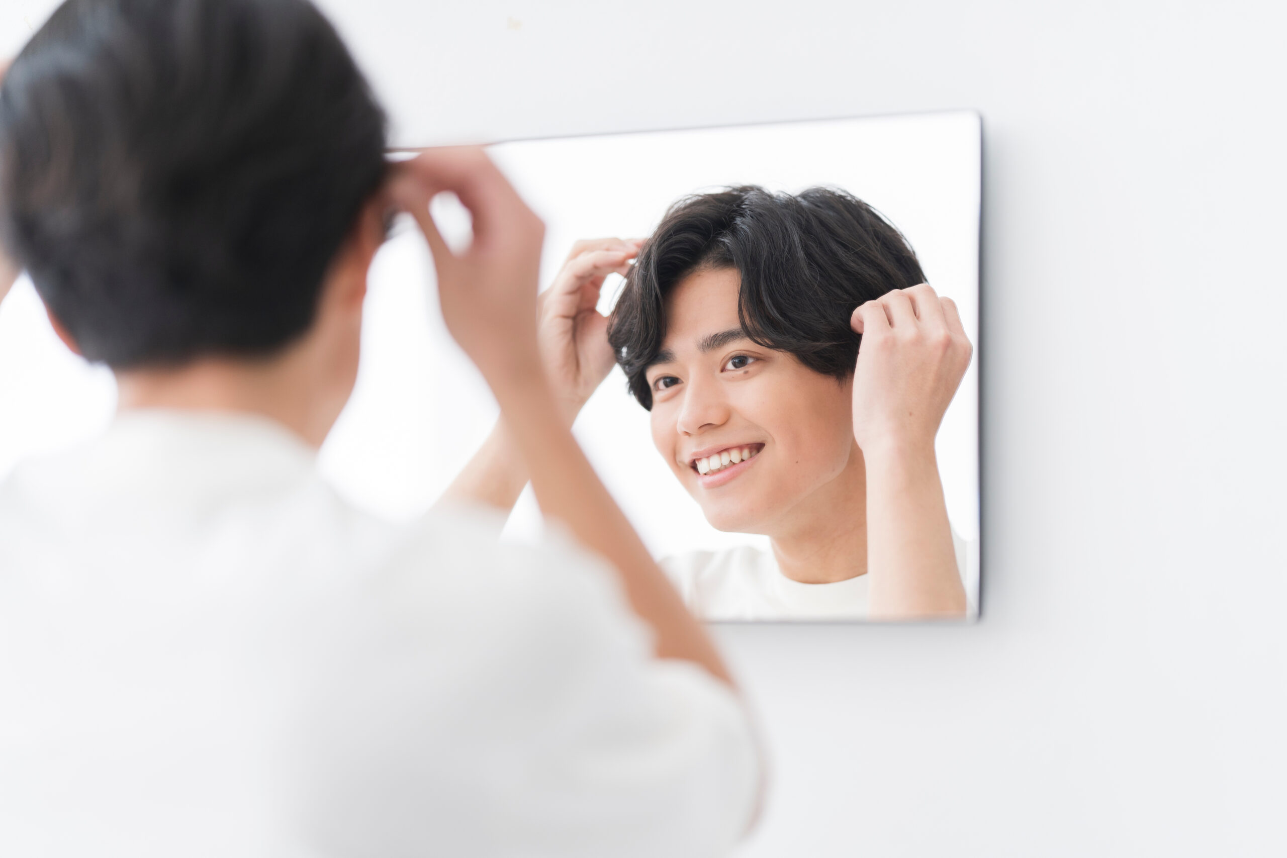 鏡を見ながらヘアセットする若い男性