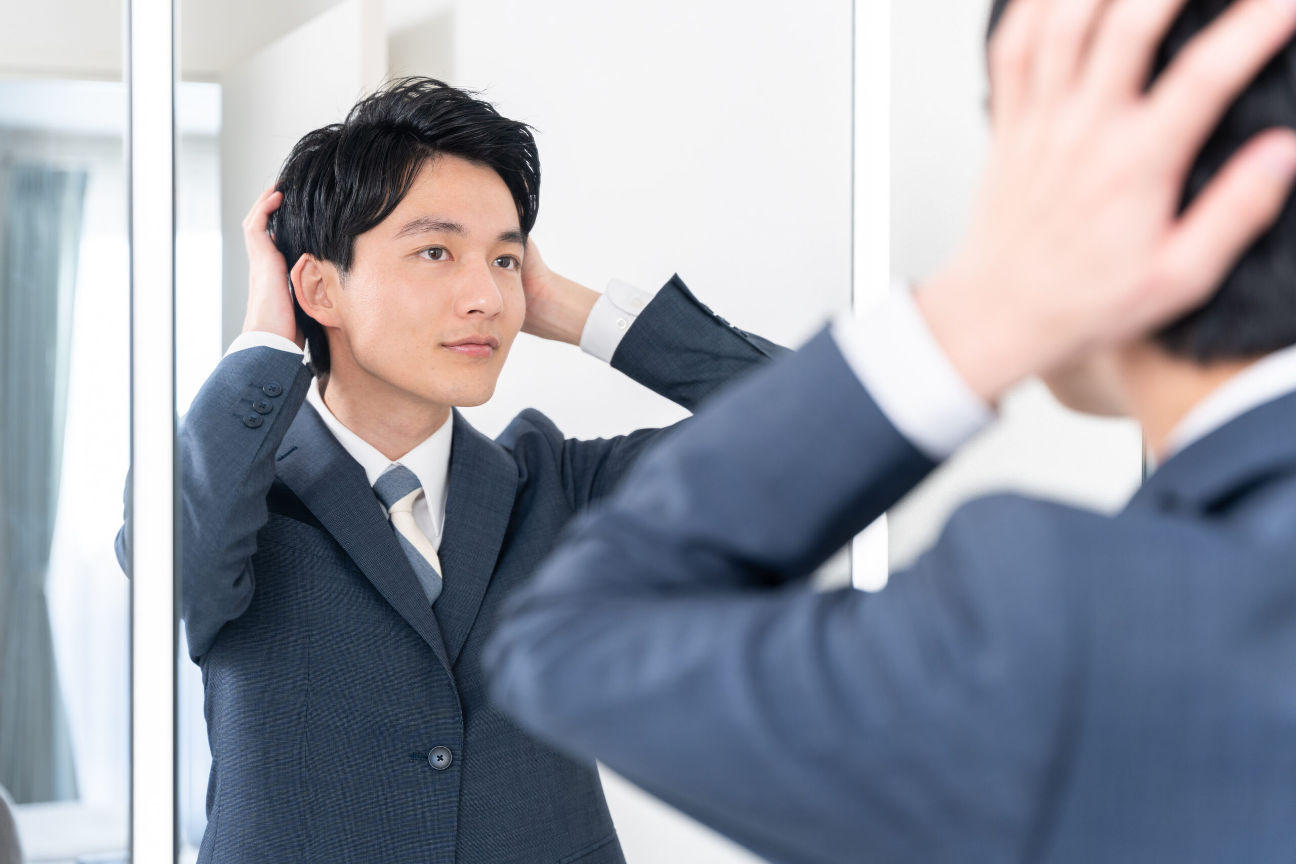 洗面所で鏡を見てヘアセットする若いビジネスマン